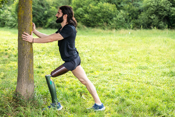 Disabled athlete amputee leg start his stretching session before running in the park outdoors