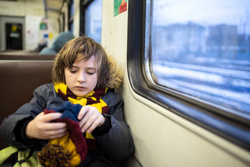 a boy sits in a suburban train by the window alone in winter