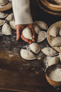 Pierogi in the making, being held in a womans hands