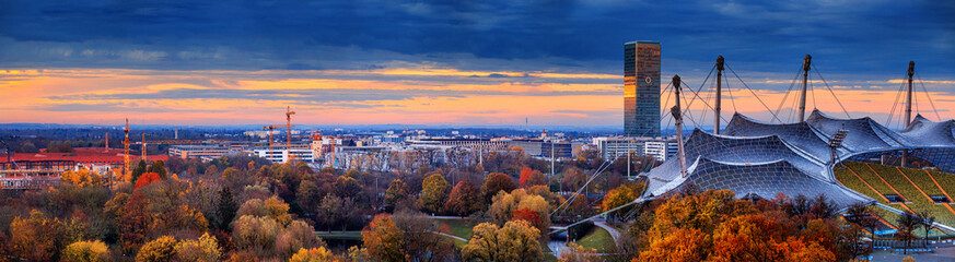 Autumn cityscape, panorama, banner - view of Munich at sunset from the Olympiapark or Olympic Park, Oberwiesenfeld neighborhood, Munich, Bavaria, Germany - obrazy, fototapety, plakaty