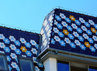 steep sloped clay ceramic tile roof with colorful blue, yellow and white flower pattern. glass roof...