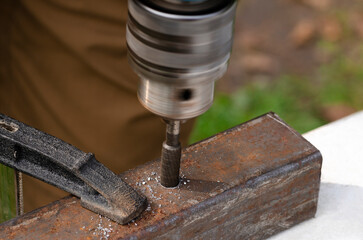 Working with metal. Men's hands with a drill