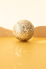 New Year and Christmas background. Christmas golden ball on a yellow background with reflection. Front view