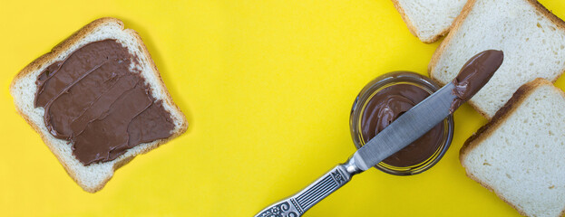 Chocolate cream, toast bread and knife on the yellow  background.Top view.Copy space.