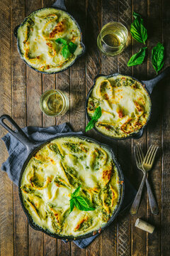 Baked Pasta in three skillets with wine glasses and basil