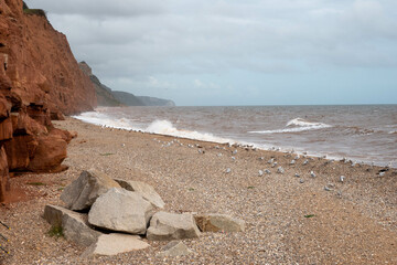 view of Sidmouth Beach and expanse of shingle and sand surrounded by ref cliffs