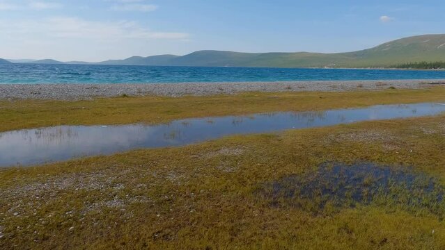 Majestic view of lake Khovsgol with beautiful mountains in the background. Blue water edge with the misty looking sky in the horizon.