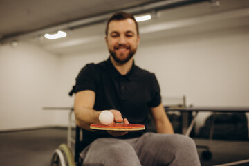 An adult disabled man in a wheelchair plays table tennis. A game of ping pong.