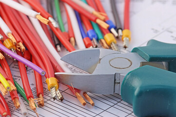 Tools for the installation of an electrical switchboard and insulated copper wires. On the electrical diagram close-up.