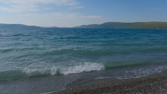 Majestic view of lake Khovsgol with beautiful mountains in the background. Blue water edge with the misty looking sky in the horizon.
