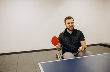 An adult disabled man in a wheelchair plays table tennis. A game of ping pong.