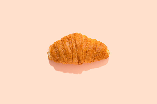 Single croissant over pink background