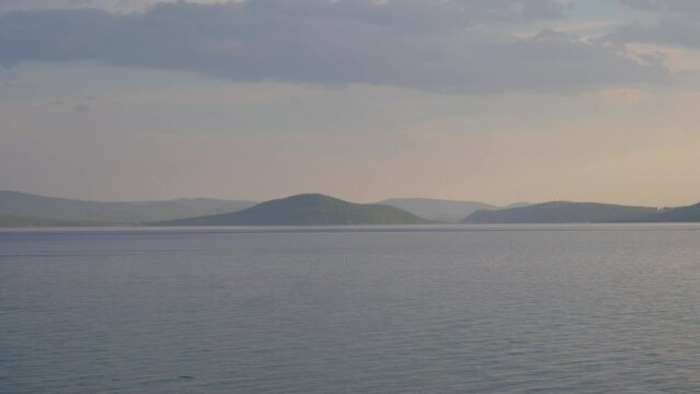 Majestic view of lake Khovsgol with beautiful mountains in the background. Blue water edge with the misty looking sky in the horizon.