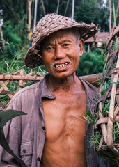 Vertical portrait of a South Asian Balinese Senior Men wearing a traditional cone-shaped hat...