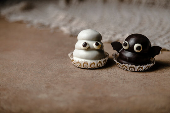 Ghost and bat  sweets over table for Halloween; made with cookie base, dulce de leche fill and chocolate coating
