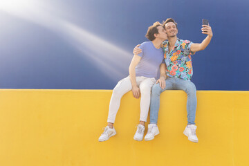  Happy young couple embraces. Two men taking selfie photo outside.