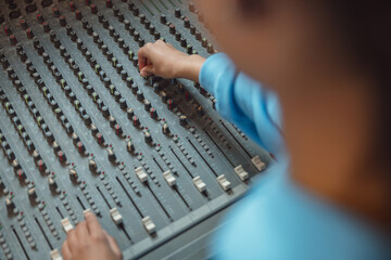 Top view of audio engineer, producer working in sound recording studio, uses mixing board, software to create new song