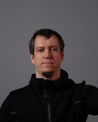 Obraz premium A man trains, sits on a blue mat, does yoga in black clothes in a dark way.