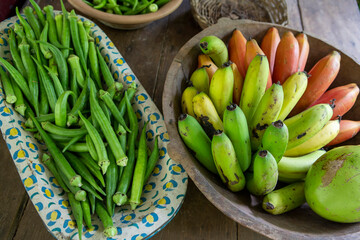 Bunches of banana and okra in rustic and decorated wooden bowls for sale after harvest in a popular economy farm. Sao Paulo state, Brazil