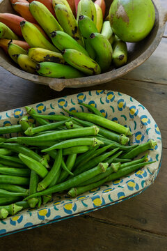 Bunches of banana and okra in rustic and decorated wooden bowls for sale after harvest in a popular economy farm. Sao Paulo state, Brazil