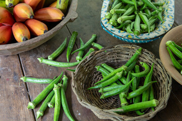 Bunches of banana and okra in rustic and decorated wooden bowls for sale after harvest in a popular economy farm. Sao Paulo state, Brazil