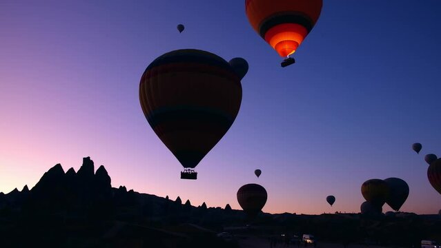 Hot air balloons flying above fairy chimneys during sunrise at Cappadocia