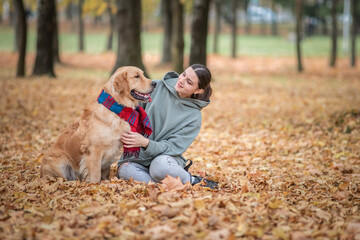 Naklejka na ściany i meble Young beautiful dark-haired girl plays with a golden retriever in the park.