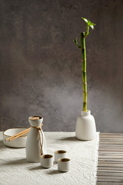 Japanese sake still life with a sprig of bamboo, light linen background, Asian ceremony