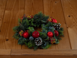 Couronne de houx sur un fond bois avec pommes de pins, boules rouges et décorations dans l'esprit de Noël.