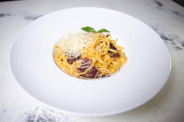 Pasta carbonara with bacon, cream and cheese on a white plate in a restaurant