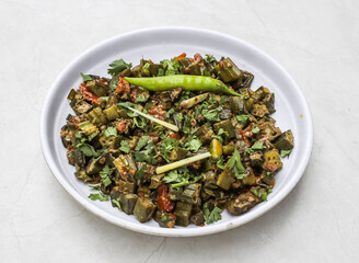 fried bhindi or lady finger with onion, ginger, tomato and green chili served in plate isolated on table top view of indian and pakistani spicy food