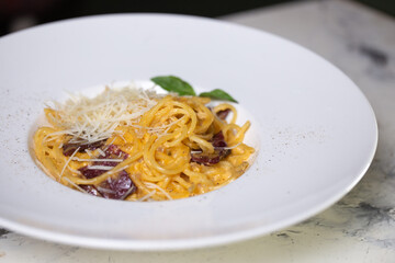 Pasta carbonara with bacon, cream and cheese on a white plate in a restaurant