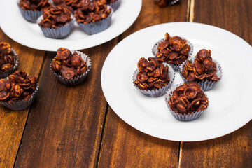 Chocolate cornflake cookies served on white plates. Chocolate cornflake cake in blue paper cupcake case