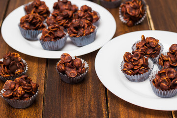 Chocolate cornflake cookies served on white plates. Chocolate cornflake cake in blue paper cupcake case