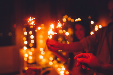 Bright festive Christmas or New Year sparkler in hand toning, group of friends celebrating together.