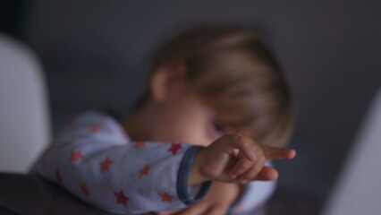 Bashful little baby boy pointing finger at laptop screen watching content