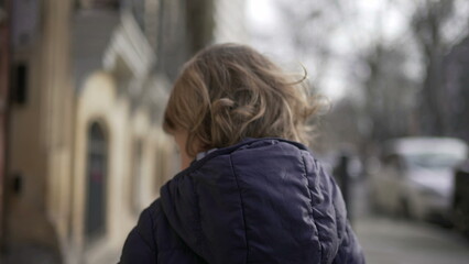 Fototapeta na wymiar Back of toddler walking in city sidewalk during winter2