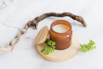 aroma candle on wooden podium with stick and green twigs