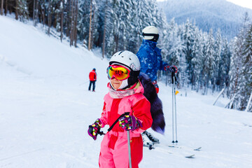 Fototapeta na wymiar Portrait of little girl skier in sports suit finishing the ride.