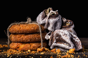 Gingerbread cookies tied with a linen rope and dried persimmon on a black background.