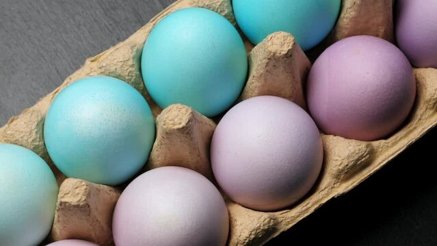 Painted easter eggs in pack. Closeup on black slate background. Rotating