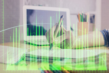 Financial forex charts displayed on woman's hand taking notes background. Concept of research. Double exposure