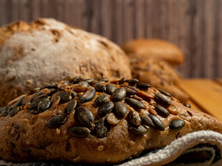 Dark bread and buns on a wooden background. Bakery products with grains.