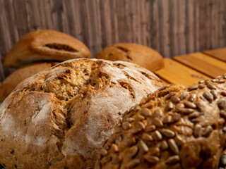 Dark bread and buns on a wooden background. Bakery products with grains.