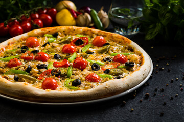 Spicy chicken pizza with olives cherry tomatoes, peppers and jalapenos