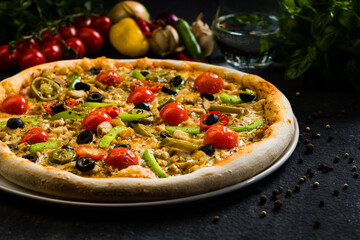 Spicy chicken pizza with olives cherry tomatoes, peppers and jalapenos