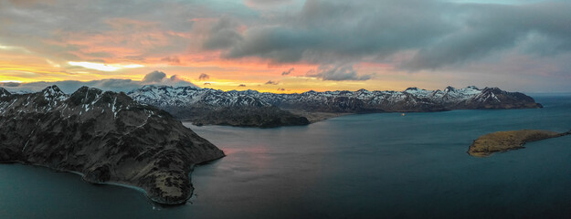 Panoramic aerial view of a mountain range with snow on the crests along the Dutch Harbour on Amaknak Island at sunset, Unalaska, Alaska, United States.