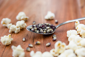 Spoonful of blue popcorn kernels on wood background, healthy snack, popcorn kernels, healthy eating