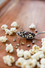 Spoonful of blue popcorn kernels on wood background, healthy snack, popcorn kernels, healthy eating