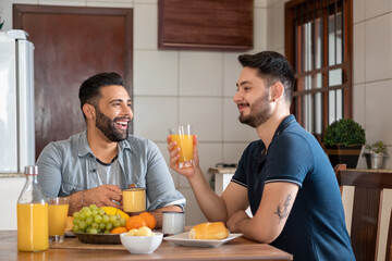 happy gay couple smiling and having breakfast at home